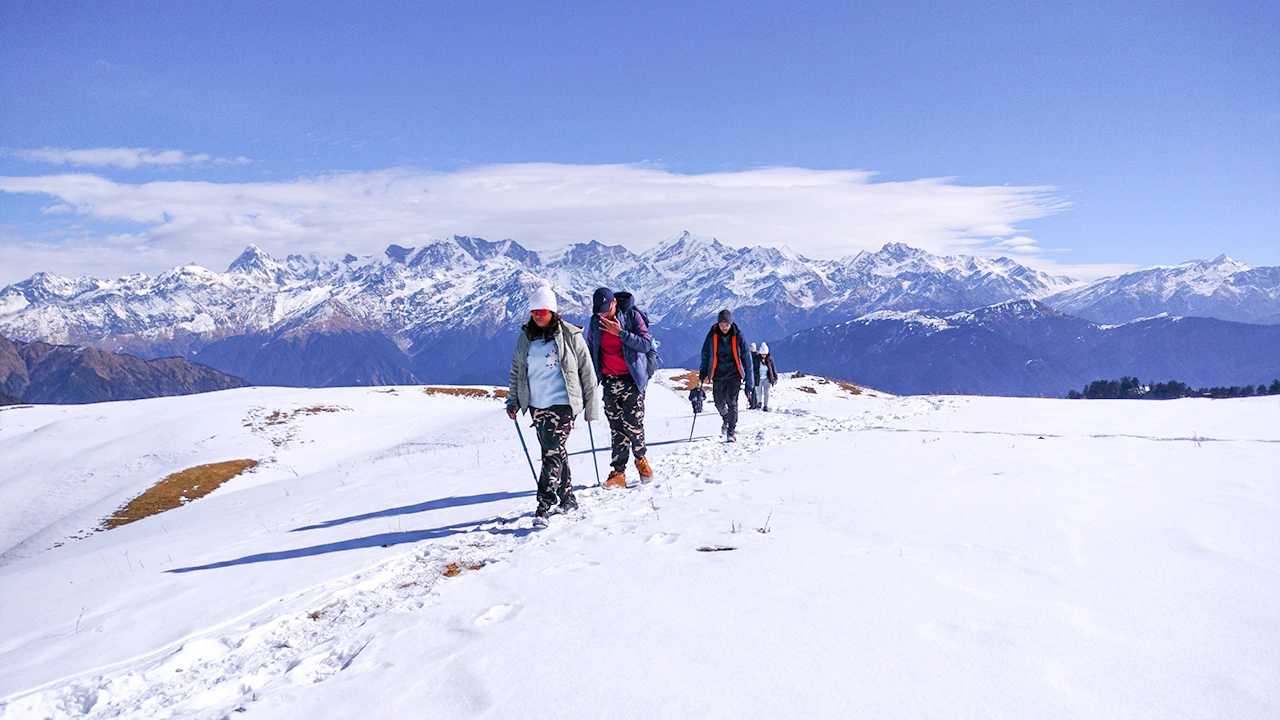 Group of hikers moving along a snowy trail during the Dayara Bugyal trek