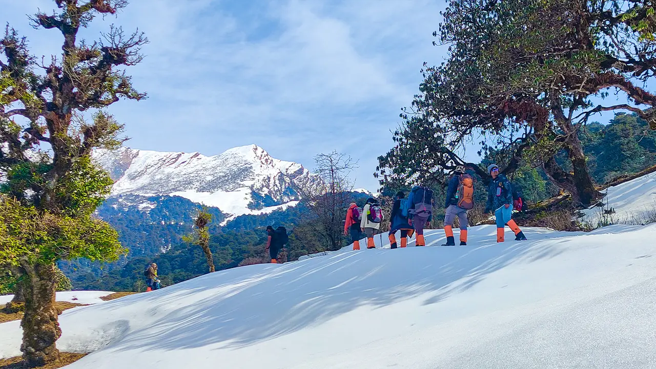 Hikers walking on a snowy path facing the Himalayan peaks during the Chopta Chandrashila trek