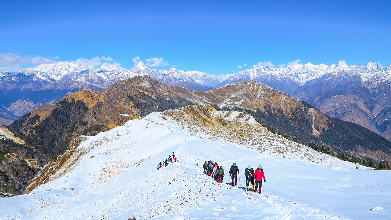 trekkers hiking along a snow-covered ridge during the Kuari Pass trek