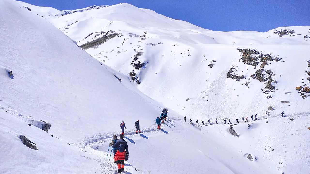 Trekkers walking through the snowy trail of the Kuari Pass Trek in the Himalayas