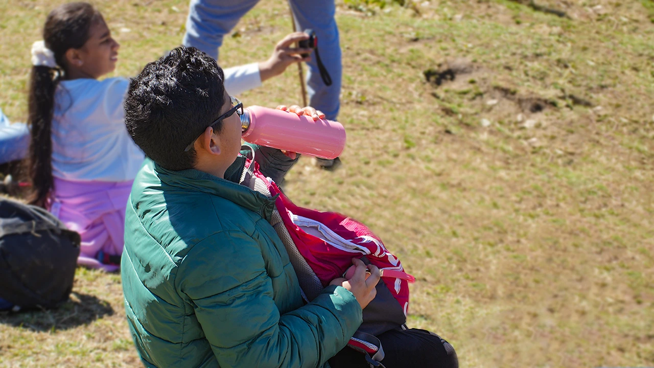 Trekker drinking water to stay hydrated during mountain trek, Trek The Himalayas